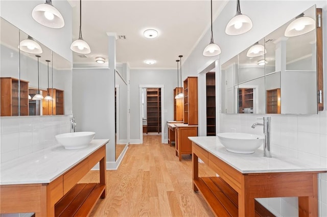 bathroom with vanity, wood-type flooring, crown molding, and backsplash