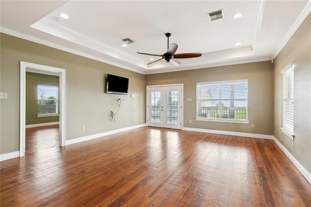 empty room featuring plenty of natural light, a raised ceiling, french doors, and hardwood / wood-style flooring