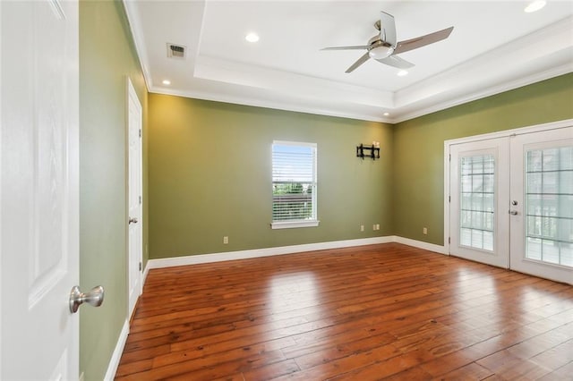 spare room featuring a raised ceiling, hardwood / wood-style floors, french doors, ornamental molding, and ceiling fan