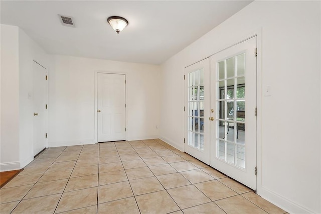 empty room with french doors and light tile patterned floors