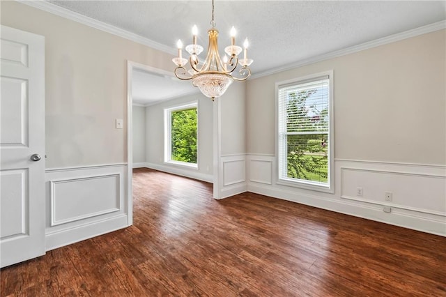 empty room with an inviting chandelier, dark wood-type flooring, a textured ceiling, and crown molding