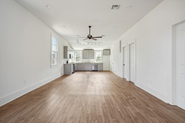 unfurnished living room with rail lighting, ceiling fan, wood-type flooring, and sink