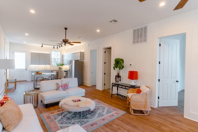 living room featuring ceiling fan, light hardwood / wood-style flooring, and sink