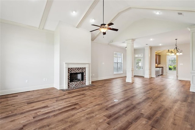 unfurnished living room featuring ceiling fan with notable chandelier, a wealth of natural light, a tile fireplace, and hardwood / wood-style flooring