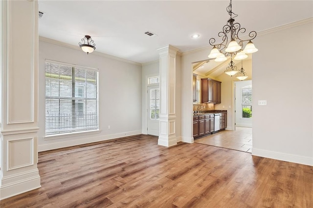 unfurnished dining area featuring decorative columns, ornamental molding, a notable chandelier, and light wood-type flooring