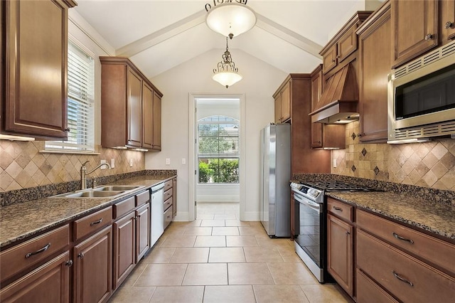 kitchen with vaulted ceiling, premium range hood, pendant lighting, sink, and stainless steel appliances