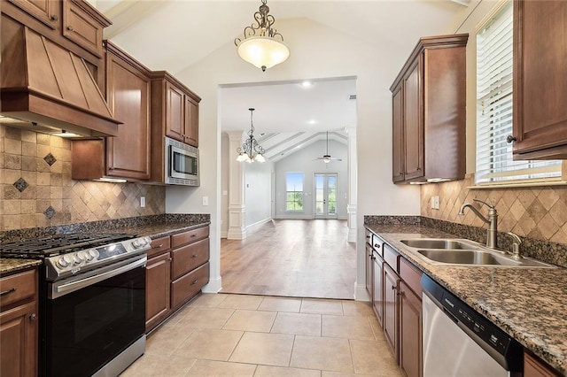 kitchen with premium range hood, lofted ceiling, sink, appliances with stainless steel finishes, and ceiling fan with notable chandelier