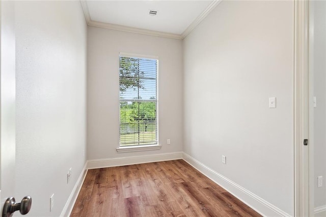 empty room with crown molding, a healthy amount of sunlight, and wood-type flooring