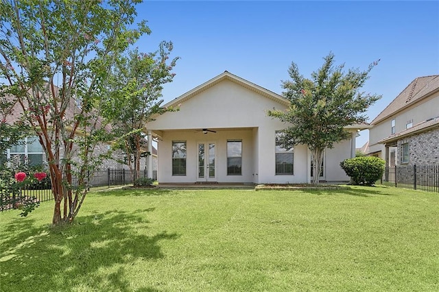 back of property with french doors, ceiling fan, and a yard