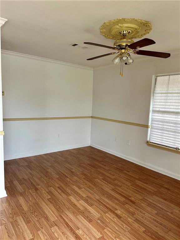 unfurnished room featuring hardwood / wood-style flooring, ceiling fan, and ornamental molding