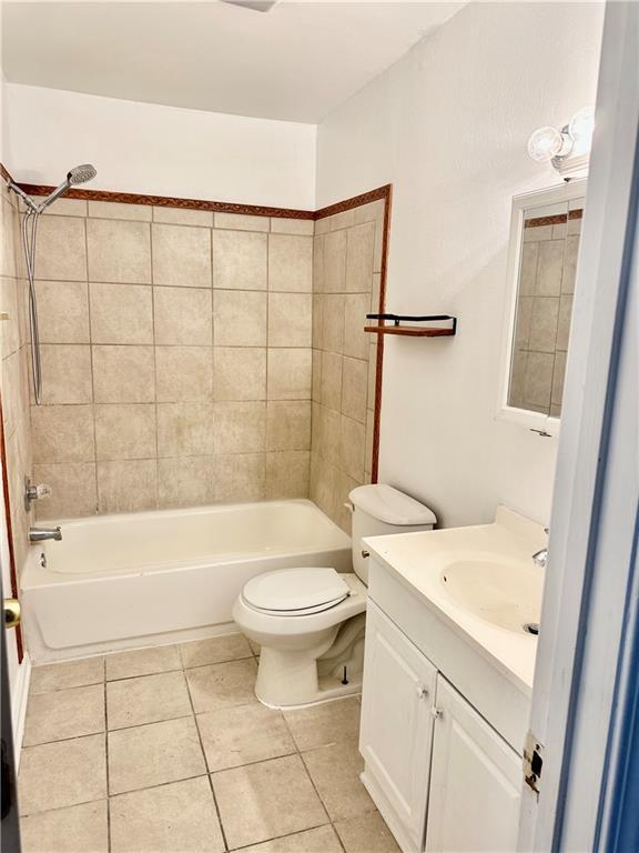 full bathroom with tile patterned floors, toilet, tiled shower / bath combo, and vanity