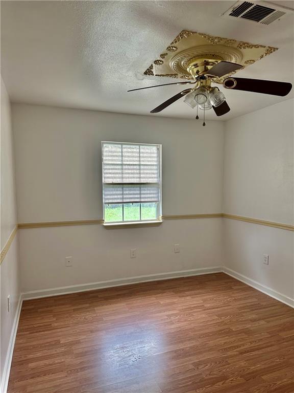 unfurnished room featuring ceiling fan, wood-type flooring, and a textured ceiling