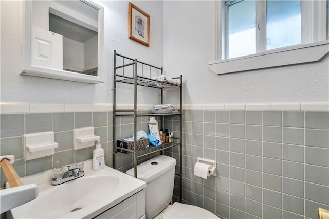 bathroom with toilet, vanity, and tile walls