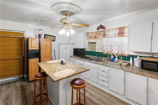 kitchen featuring sink, white cabinets, a kitchen bar, and light stone counters