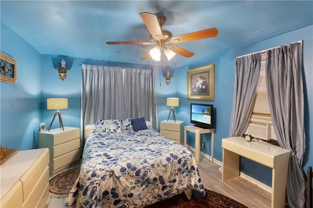 bedroom featuring cooling unit, ceiling fan, and light wood-type flooring