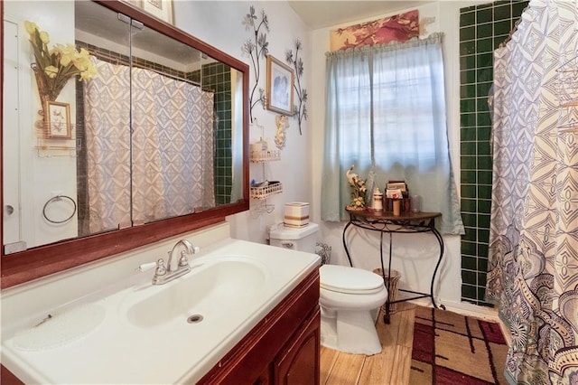 bathroom with wood-type flooring, a shower with curtain, vanity, and toilet