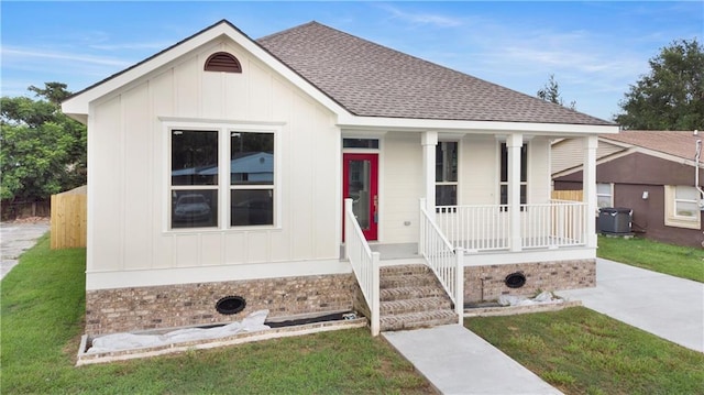 view of front of house with central AC, a front lawn, and covered porch