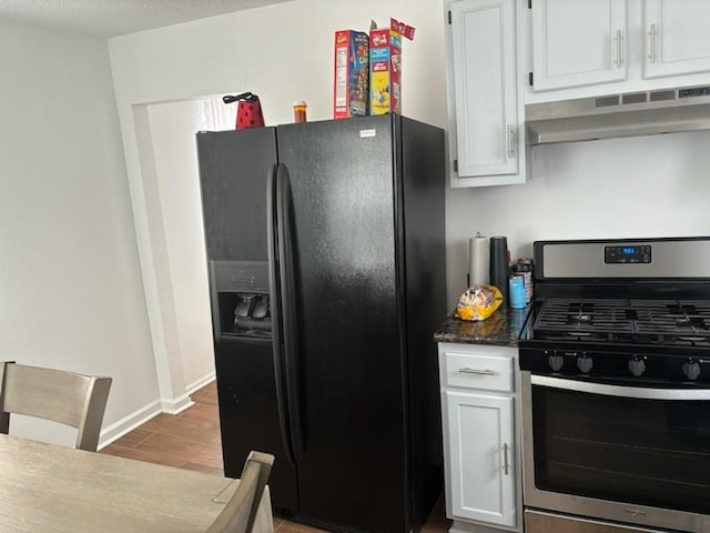 kitchen featuring white cabinetry, black fridge, stainless steel range with gas stovetop, and wood-type flooring