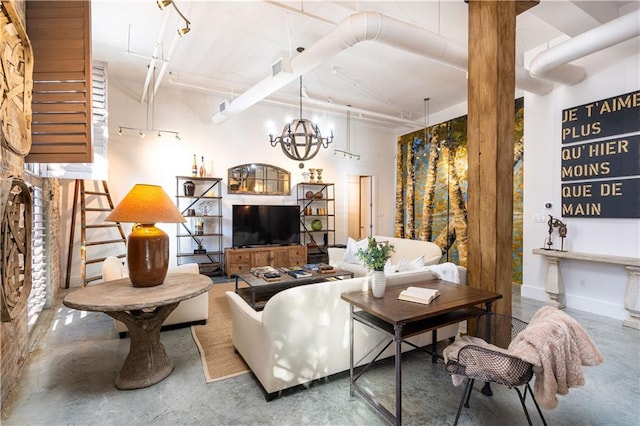 living room with a chandelier and concrete flooring