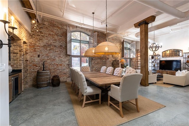 dining space with a wood stove, a high ceiling, brick wall, and concrete floors