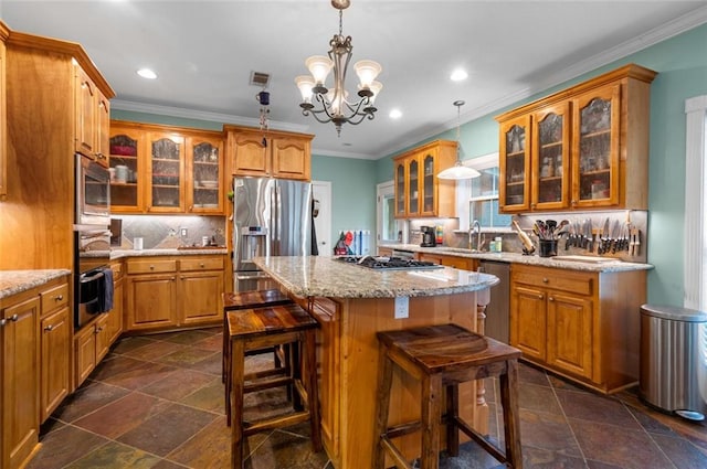 kitchen with decorative light fixtures, a kitchen island, appliances with stainless steel finishes, and an inviting chandelier