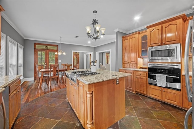 kitchen featuring appliances with stainless steel finishes, light stone counters, pendant lighting, a chandelier, and a center island