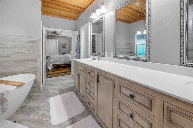 bathroom with vanity, wooden ceiling, a bathing tub, ceiling fan, and tile walls