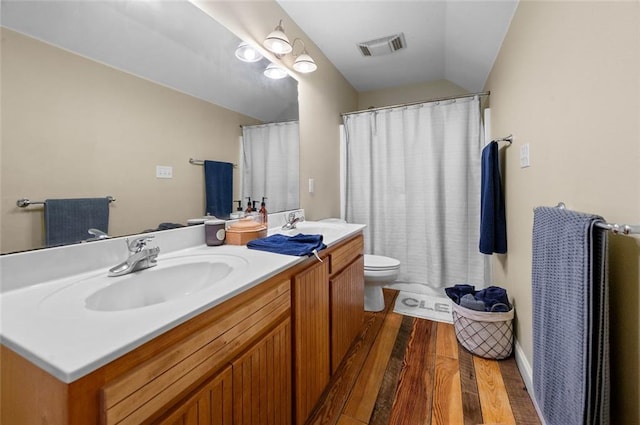 bathroom featuring hardwood / wood-style floors, vanity, vaulted ceiling, and toilet