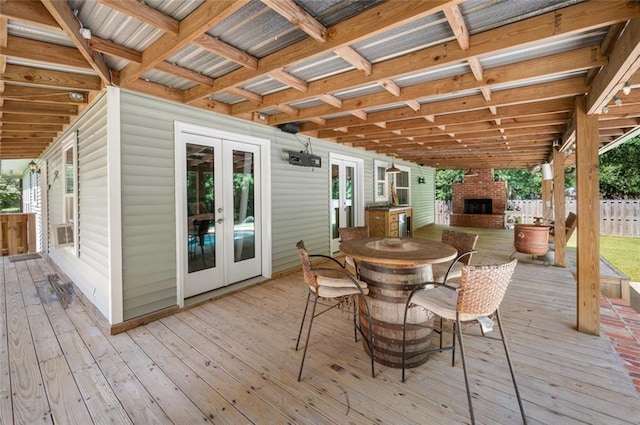 wooden terrace with an outdoor brick fireplace and french doors