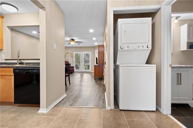 washroom featuring stacked washer / drying machine, ceiling fan, sink, a textured ceiling, and light tile patterned floors