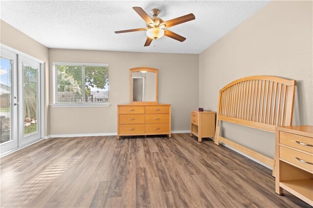 unfurnished bedroom with dark wood-type flooring, a textured ceiling, and ceiling fan