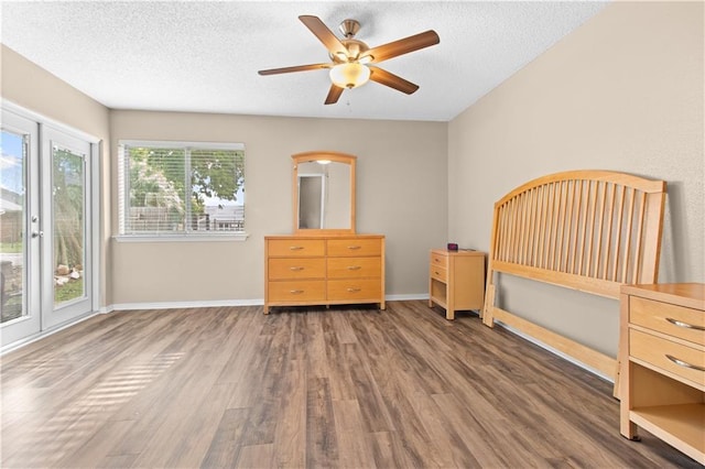 unfurnished bedroom featuring dark hardwood / wood-style flooring, ceiling fan, and a textured ceiling