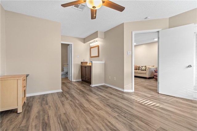 unfurnished bedroom with hardwood / wood-style flooring, a textured ceiling, ensuite bathroom, and ceiling fan