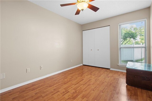 unfurnished bedroom featuring ceiling fan, light hardwood / wood-style flooring, and a closet