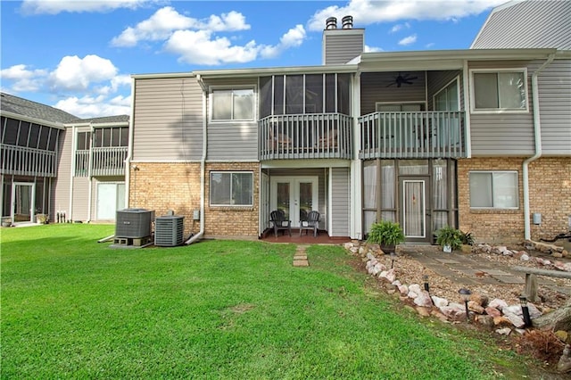 rear view of property with a balcony, central AC unit, french doors, and a yard