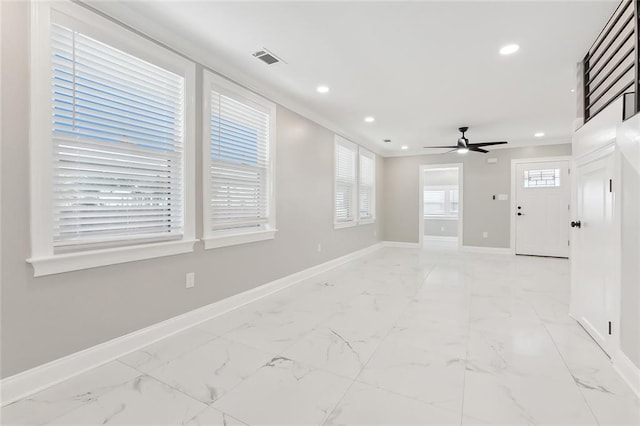 empty room with crown molding, a wealth of natural light, and ceiling fan