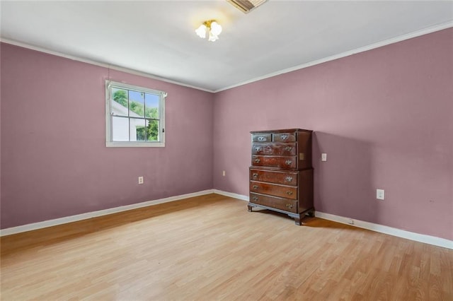 spare room with wood finished floors, ornamental molding, and baseboards