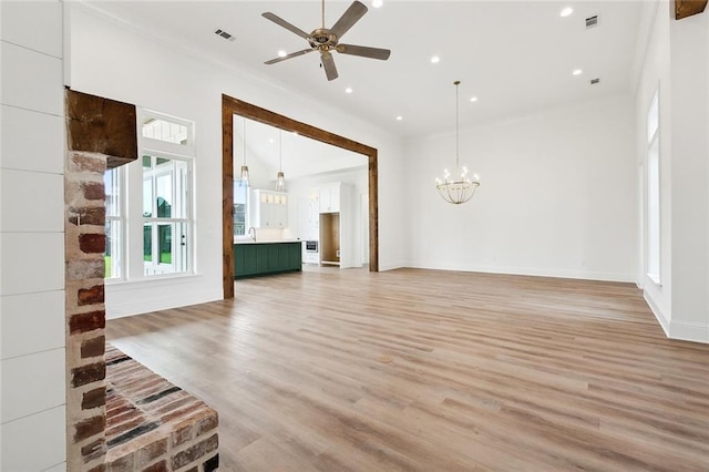 unfurnished living room with ceiling fan with notable chandelier, light hardwood / wood-style floors, and ornamental molding