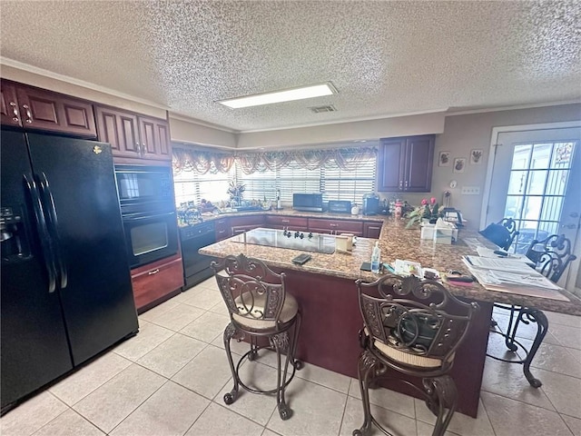 kitchen featuring a breakfast bar area, black appliances, kitchen peninsula, light tile patterned floors, and light stone countertops