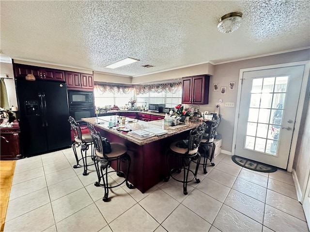 kitchen with black appliances, a breakfast bar, a textured ceiling, light tile patterned flooring, and ornamental molding