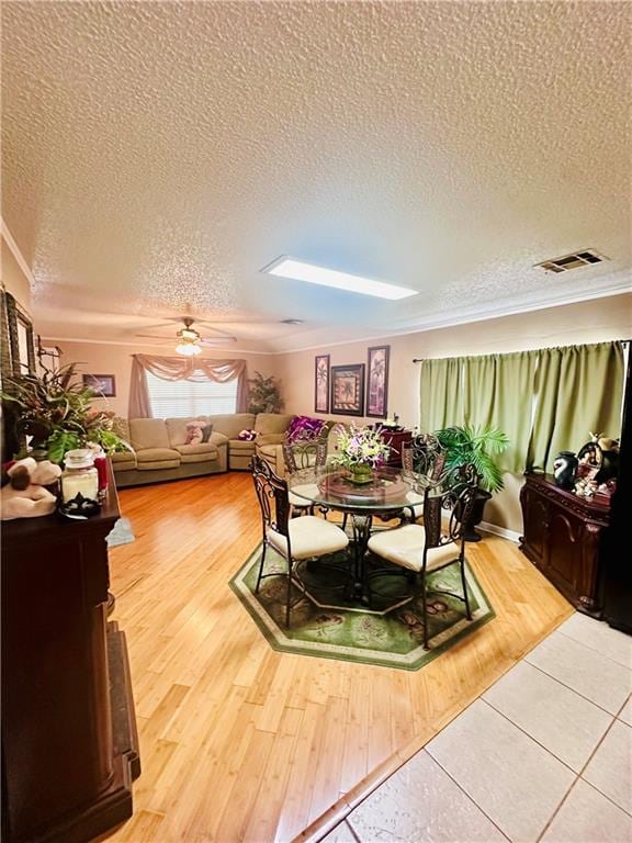 dining space featuring ceiling fan, ornamental molding, hardwood / wood-style floors, and a textured ceiling