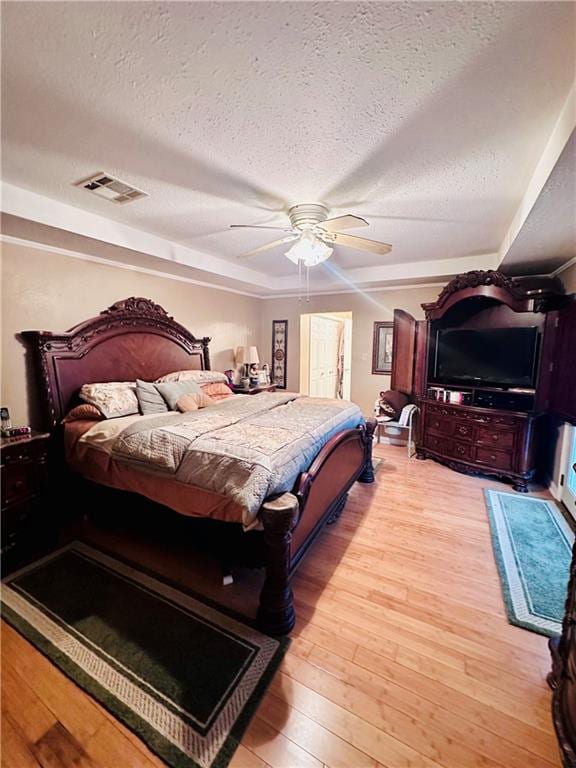 bedroom with a textured ceiling, light wood-type flooring, and ceiling fan