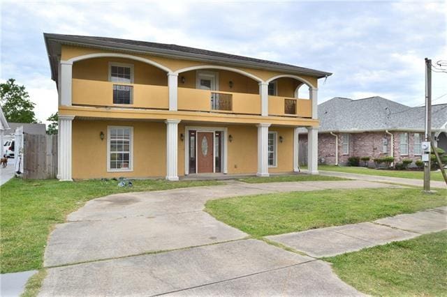 view of front of property featuring a balcony and a front yard