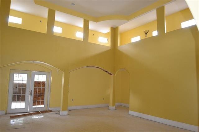 unfurnished living room featuring french doors and a towering ceiling