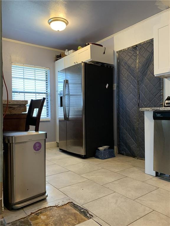 kitchen featuring dark stone countertops, light tile patterned flooring, crown molding, appliances with stainless steel finishes, and white cabinets