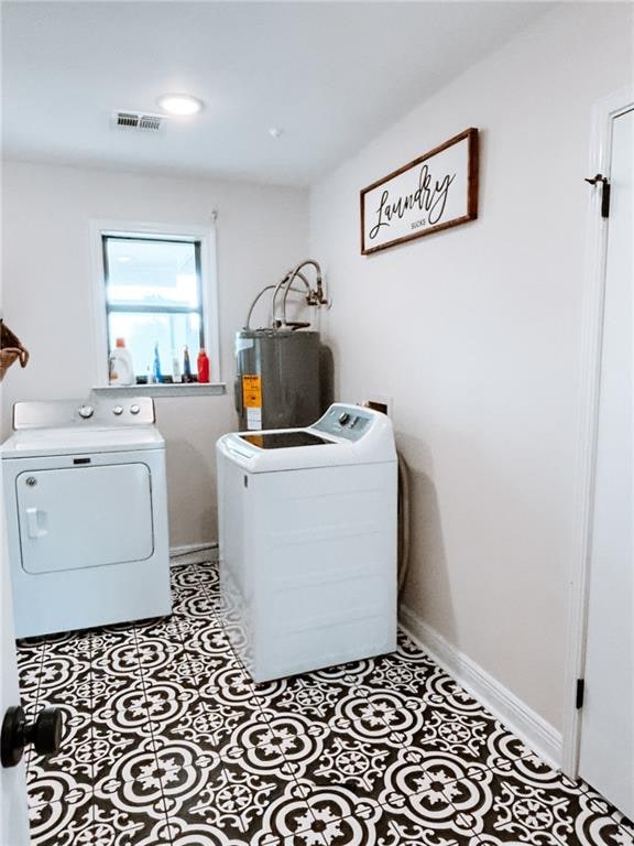 washroom featuring water heater, light tile patterned floors, and washer and clothes dryer