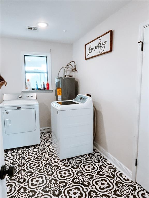 washroom featuring laundry area, visible vents, washer and clothes dryer, and water heater