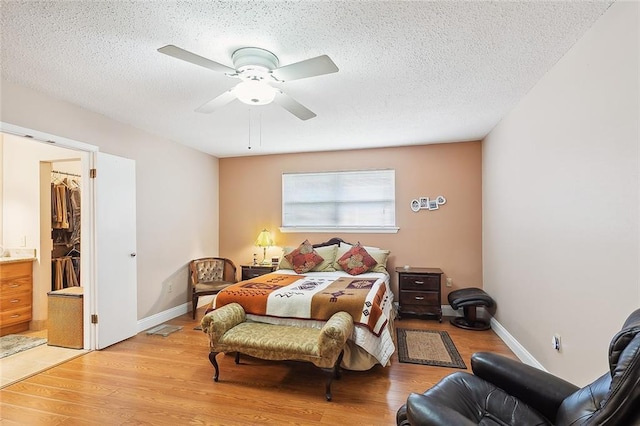 bedroom featuring light hardwood / wood-style flooring, ceiling fan, a textured ceiling, a spacious closet, and a closet