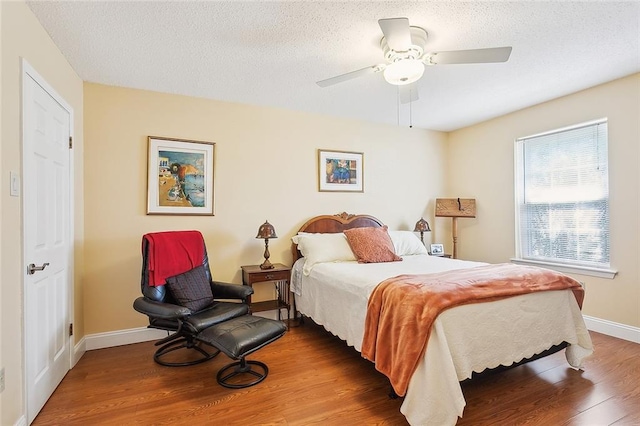 bedroom with hardwood / wood-style flooring, a textured ceiling, and ceiling fan