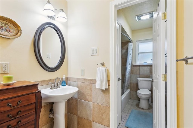 bathroom featuring shower / bathtub combination with curtain, toilet, tile patterned flooring, and tile walls